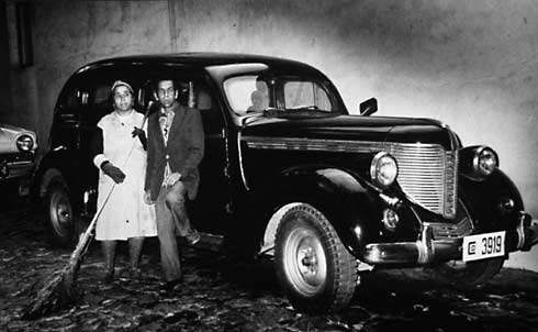 Poor Man and Woman in Front of Rich Car - 1970 - $2200